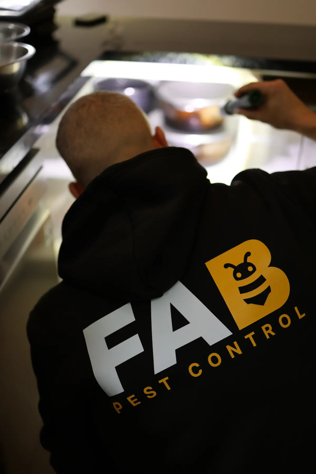 Fabien from FAB Pest Control inspecting a kitchen area with a torch for signs of cockroach activity.