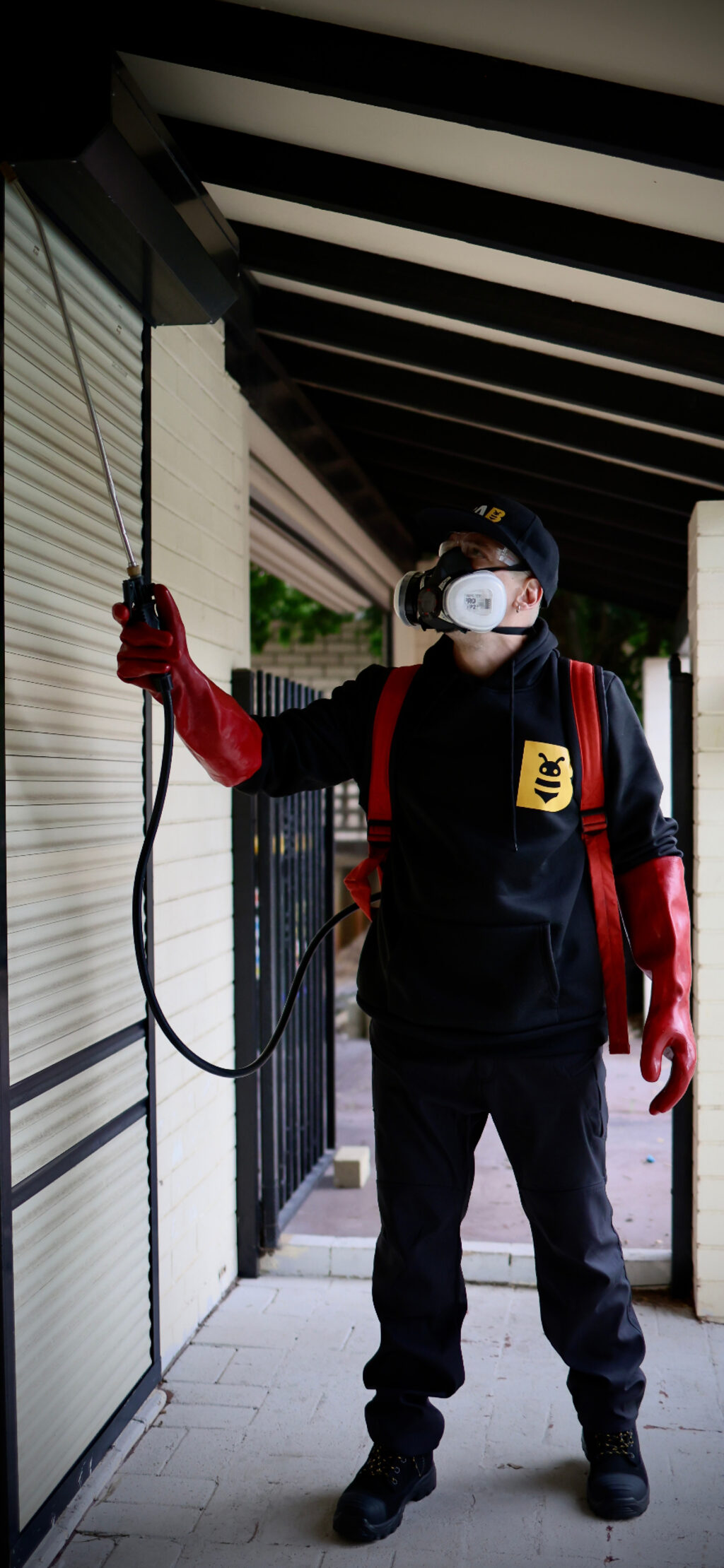 Fabien from FAB Pest Control treating exterior wall and eave areas for spider activity.