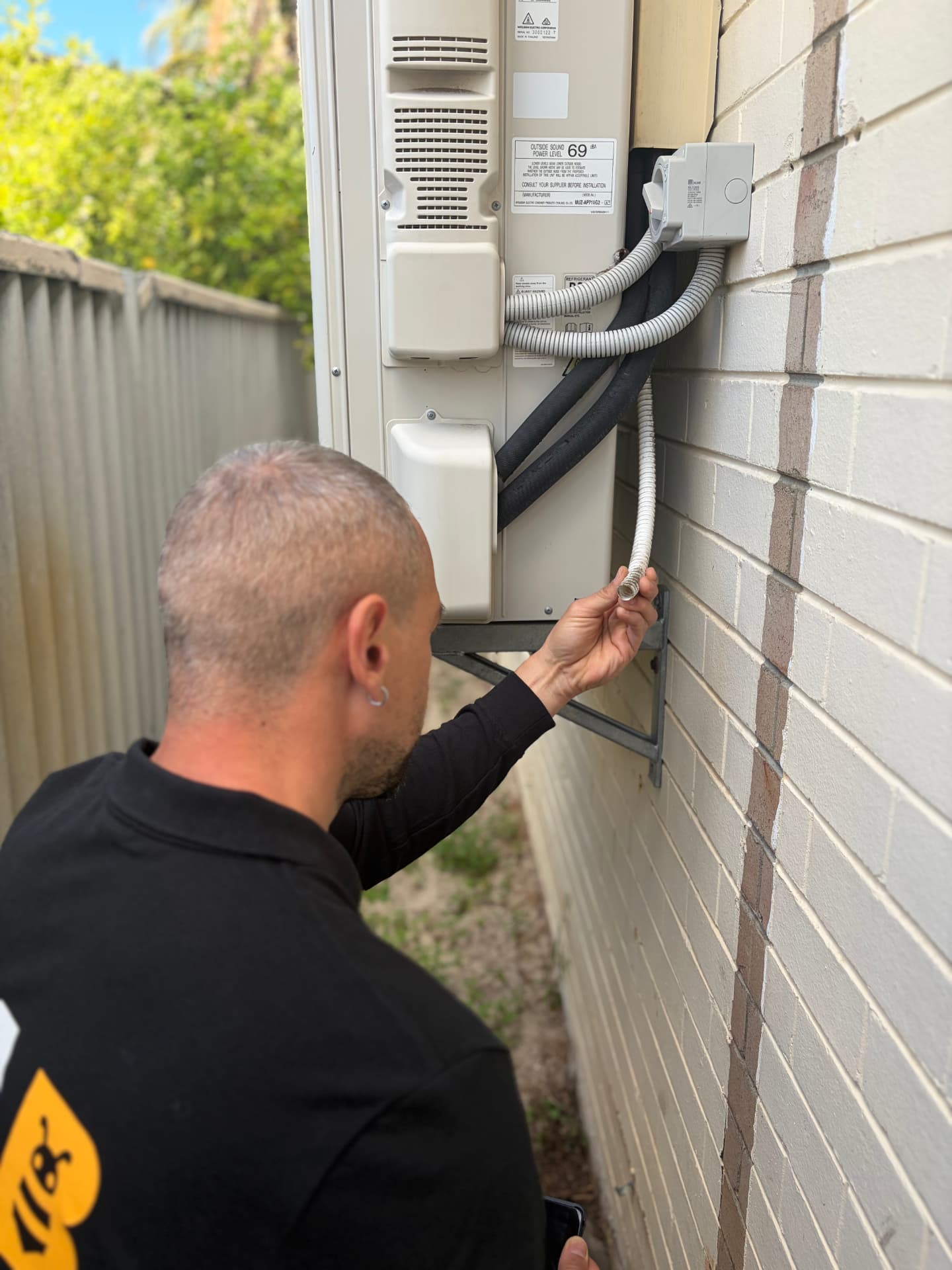Fabien checking an air-conditioning overflow near the building for termite risk conditions